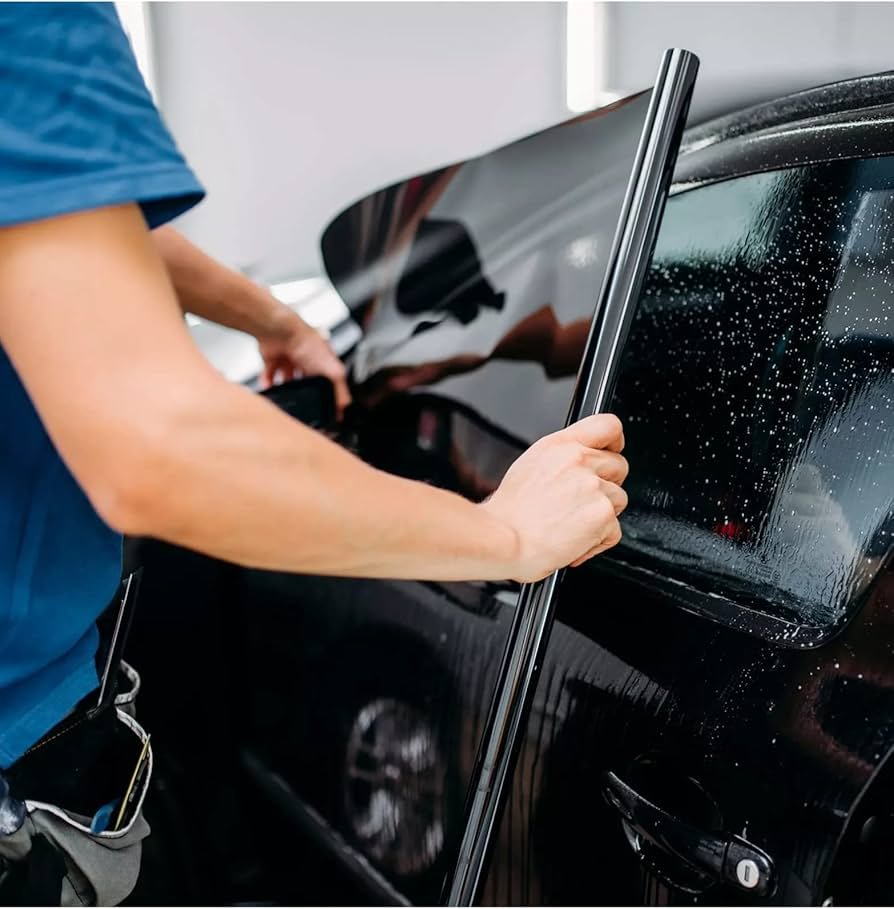 Technician applying window tint film to a car